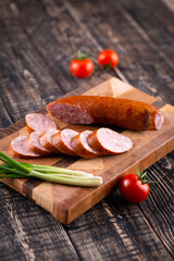 Fresh sausages and ham slices on wooden cutting board, delicious snack, spicy and high quality meat products made of pork and veal, beef.