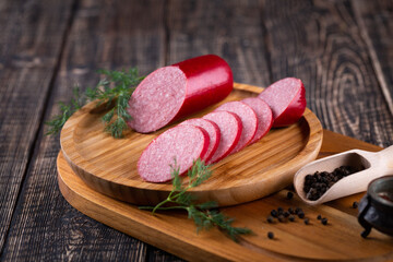 Fresh sausages and ham slices on wooden cutting board, delicious snack, spicy and high quality meat...