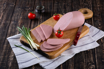 Fresh sausages and ham slices on wooden cutting board, delicious snack, spicy and high quality meat...