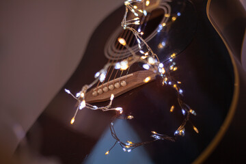 Christmas at music school concept. Acoustic guitar closeup with fairy lights. Musical instrument for winter holidays. Music for Christmas party.