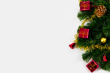 Christmas tree decorations background with copy space, pine tree with red gift boxes, red bell and gold ornament on white background