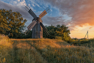 Fototapeta na wymiar Old wooden windmill at dramatic sunset, historic outdoor background