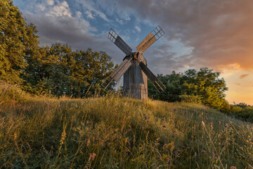 Fototapeta na wymiar Old wooden windmill at dramatic sunset, historic outdoor background