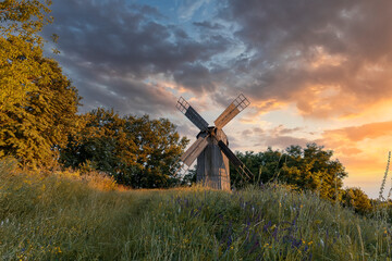 Plakat Old wooden windmill at dramatic sunset, historic outdoor background