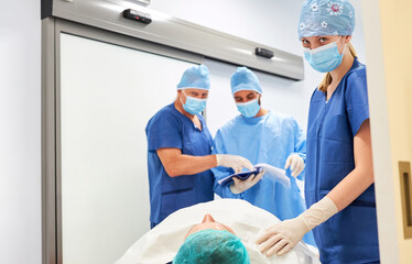 Surgeons with medical records planning the operation of a patient