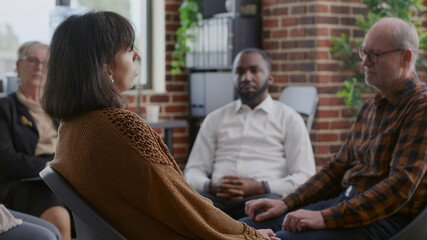 Close up of sad woman making confession about therapy and addiction at aa meeting in circle. Adult...
