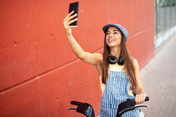 Fototapeta na wymiar Beautiful woman taking selfie photo. Beautiful happy lady with electric bicycle.