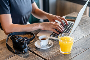 Fototapeta na wymiar Businesswoman hand working at a café. woman using laptop, female hands typing, writing notes, studying languages, distance learning concept, checking email in morning, drink coffee