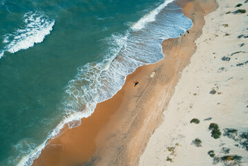 Aerial shot of seashore and crashing waves. Beautiful sandy beach and amazing turquoise tropical sea waters. Perfect summer seascape.