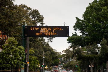 Changeable electronic dynamic road sign reads: 'Stay COVID safe. Unwell. Get tested' on the city...
