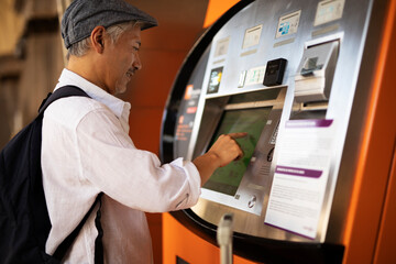 Senior man withdrawing money from credit card. Man typing pin code on keypad of ATM mashine..	