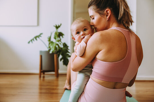 Caring mom working out with her baby at home