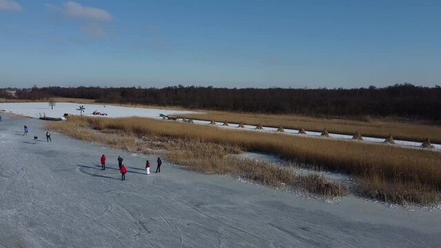 Ice skating people on a frozen canal in the Wieden Weerribben nature reserve during a beautiful winter day in The Netherlands. Aerial drone point of view.