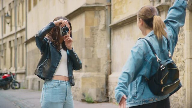 Same sex female couple taking photos of each other on retro digital camera around Oxford UK together - short in slow motion