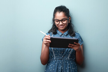 Portrait of a smiling girl of Indian ethnicity holding a tablet phone in hand 