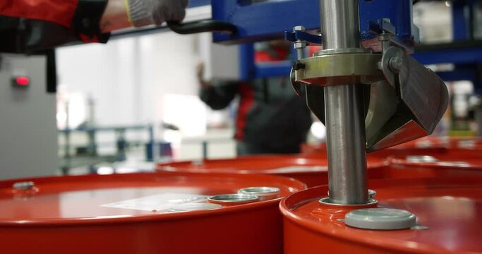 Machine oil production plant. Red metal barrel move along the conveyor line to dispense engine oil. Development, storage and supply of lubricants for industrial enterprises. Shot with RED camera.