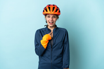 Young cyclist woman isolated on blue background with surprise facial expression