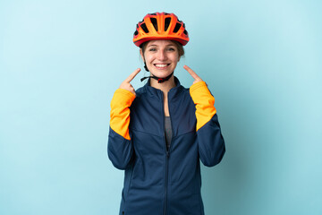 Young cyclist woman isolated on blue background giving a thumbs up gesture