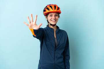 Young cyclist woman isolated on blue background counting five with fingers - obrazy, fototapety, plakaty