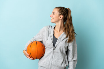 Young caucasian woman isolated on blue background playing basketball