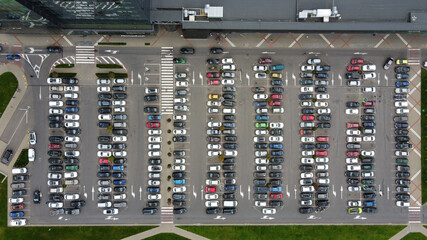 Aerial top view of parking lot with cars near the business center and supermarket. Many cars are parked in a parking lot with white markings. © Jul