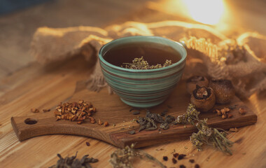 fragrant herbal tea in a cup, stands on a wooden surface next to dry herbs and berries