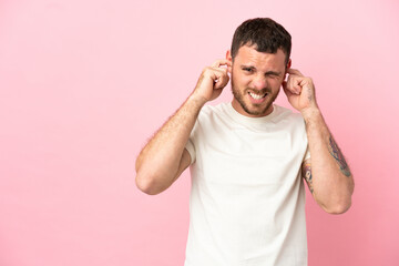 Young Brazilian man isolated on pink background frustrated and covering ears