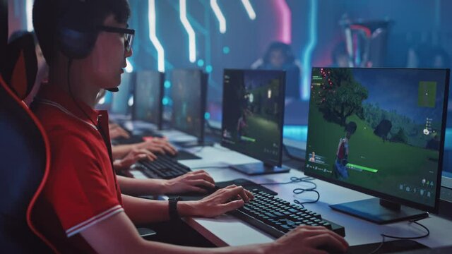 Professional Gamer Plays in a Video Game on Championship. Computer Screens Show 3D Shooter Gameplay in Arcade Online Multiplayer Battle Royale. Team of Players in Stylish Cyber Games Tournament Arena