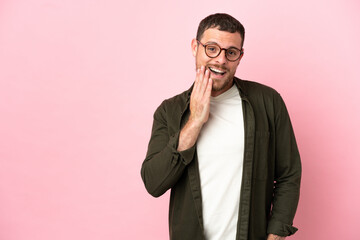 Young Brazilian man isolated on pink background looking up while smiling