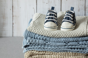baby shoes clothes and textiles on wooden background, newborn baby concept