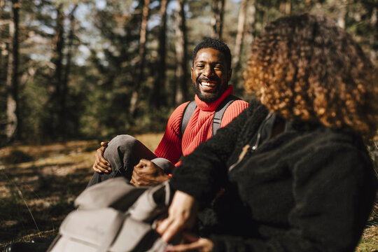 Happy man talking with girlfriend in forest during vacation