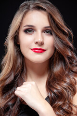 Close up studio Portrait of Beautiful caucasian woman with long brown hair and bright red lips against black background.