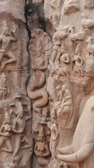 Arjuna's penance - ancient. Statues carved into rock the wall. The rock wall is located in the background.