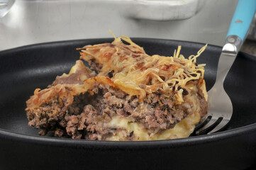 Portion de hachis parmentier dans une assiette avec une fourchette en gros plan