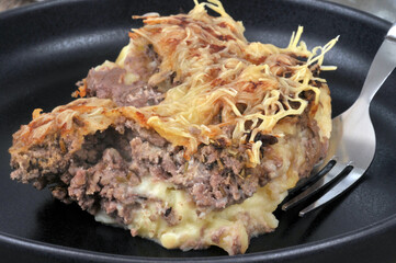 Portion de hachis parmentier dans une assiette avec une fourchette en gros plan