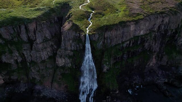 Long dramatic revolving aerial shot of waterfall in Iceland flowing it ocean. Revolves fully around to reveal the scenery.