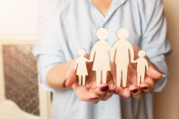 Female hands are holding a wooden figurine of a family. Selective focus. Family creation and planning concept. Family care - hands with a wooden silhouette.
