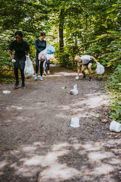 Young female and male volunteers plogging at park