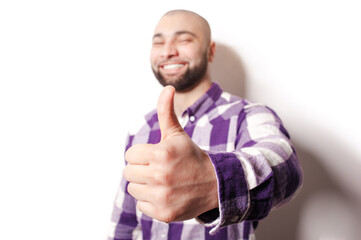 Success! Great job! Happy young bearded man showing his thumb up while standing against white background. Focus on hand.