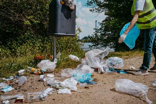Low section of male volunteer collecting plastic waste in garbage bin