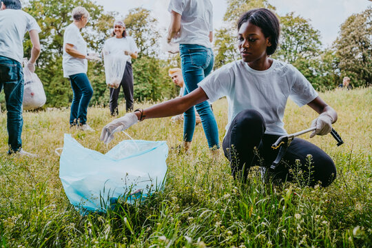 Young female environmentalist picking up plastic waste in park