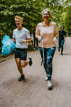 Cheerful female and male plogging with plastic bag in park