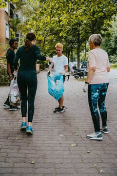 Female and male volunteers picking up plastic waste on footpath