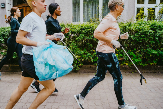 Male and female environmentalists plogging with plastic bag on footpath