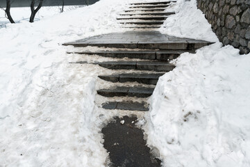 Concrete stone staircase covered with dirty deep slippery snow after blizzard snowstorm snowfall at...