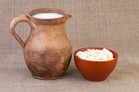 Clay jug and cup of milk and curds on rough fabric