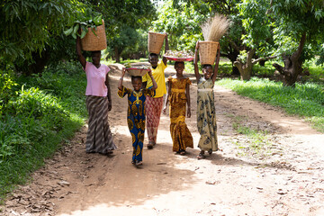 Group of smiling black African girls carrying their goods to the weekly village market