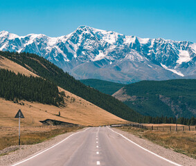 Fototapeta premium Empty asphalt road in front of huge majestic mountains with snow covered peaks. Beautiful landscape of Altay region, Russia.