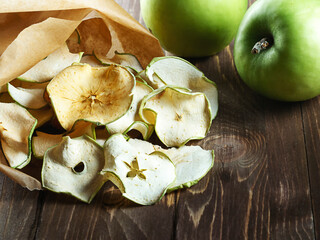 Apple chips on a wooden background.