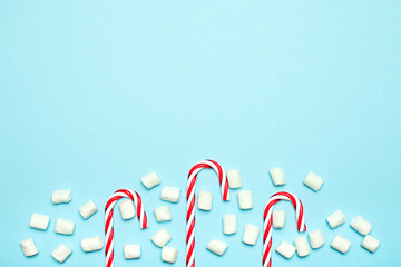 Traditional Christmas candy cane, lollipop, white marshmallows on blue background. Creative new year food concept. Christmas holiday 
